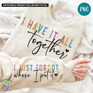 May include: A beige sweatshirt with the text "I HAVE IT ALL TOGETHER" in rainbow colors and a heart. The text "I JUST FORGOT WHERE I PUT IT" is also on the sweatshirt in rainbow colors with a heart.