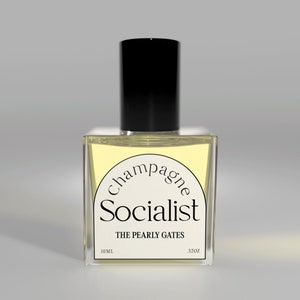 May include: A clear glass bottle with a black cap and a yellow label that reads "Champagne Socialist The Pearly Gates 10ML .32OZ".