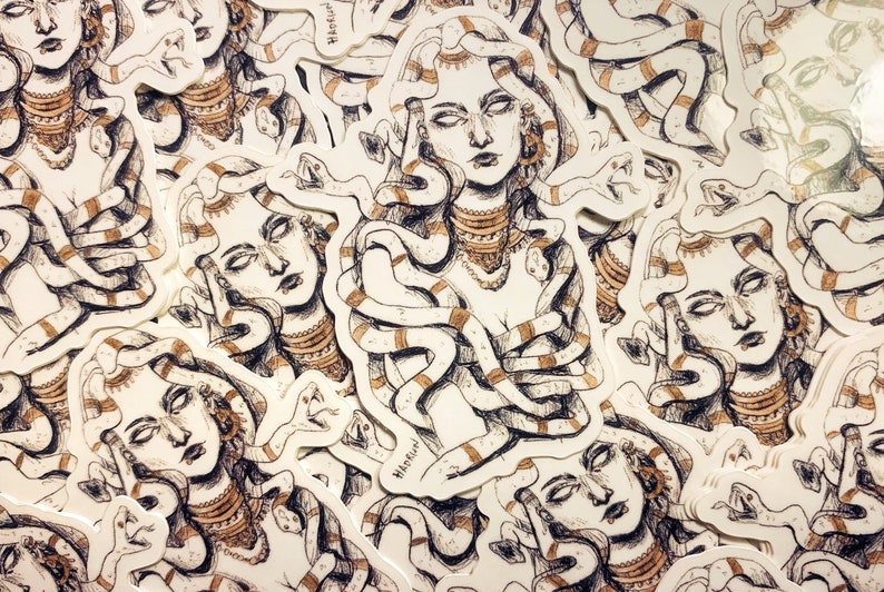 Op de afbeelding: Een verzameling Medusa-stickers. Elke sticker toont een gedetailleerde illustratie van Medusa met slangen als haar, versierd met sieraden. Het kunstwerk is in bruine en witte tinten, met een handgetekende esthetiek.