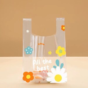 Puede incluir: Una bolsa de pl&aacute;stico transparente con un dise&ntilde;o floral y el texto "All the best". La bolsa est&aacute; llena de fruta y tiene un fondo blanco.