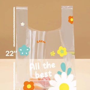 Puede incluir: Bolsa de pl&aacute;stico transparente con un dise&ntilde;o floral. La bolsa mide 56 cm de alto y 32 cm de ancho. La bolsa tiene un asa y dice "All the best" en texto blanco.