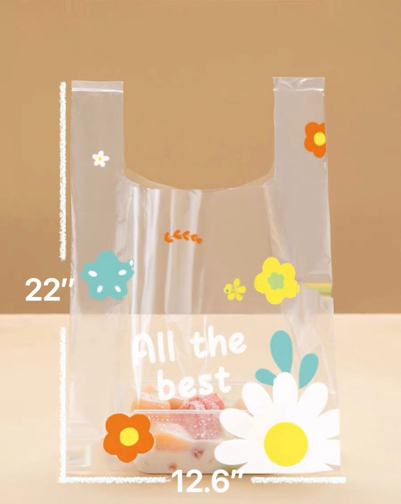 Puede incluir: Bolsa de pl&aacute;stico transparente con un dise&ntilde;o floral. La bolsa mide 56 cm de alto y 32 cm de ancho. La bolsa tiene un asa y dice "All the best" en texto blanco.