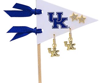 May include: A white triangular pennant on a wooden stick with two blue ribbons, featuring the blue UK logo, two gold star-shaped stud earrings with clear stones, and two gold hoop earrings with UK logo charms and clear stones.