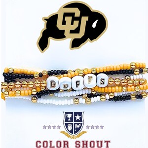 May include: Stack of beaded bracelets in black, gold, white, and orange. The bracelets spell out "BUFFS" with white letter beads. A black and gold buffalo logo is at the top, and the words "COLOR SHOUT" are at the bottom.