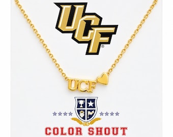 May include: A gold-toned necklace featuring a pendant with the letters UCF and a small heart shape. The necklace is displayed on a white card with the UCF logo, a shield emblem, and the text COLOR SHOUT printed in red at the bottom.