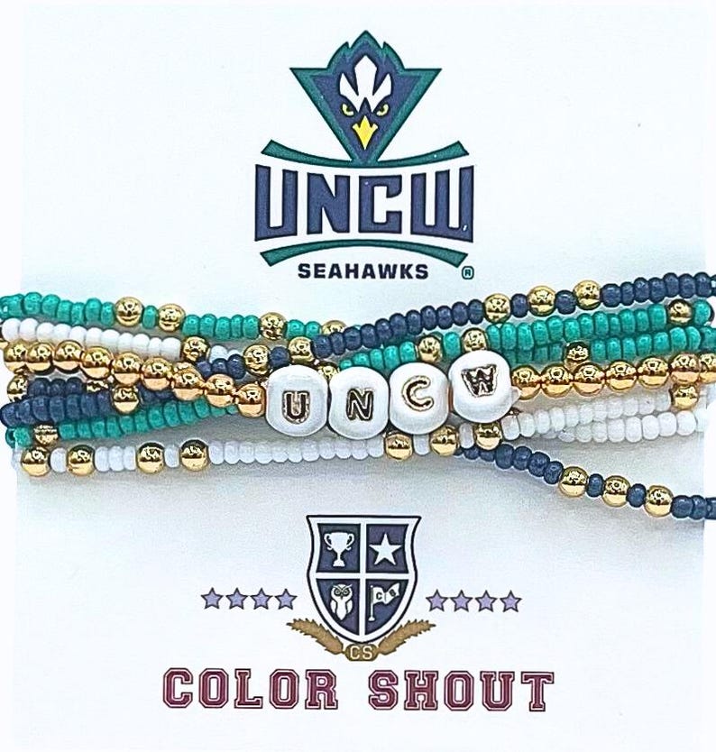 K&ouml;nnte beinhalten: Mehrfarbige Perlenarmb&auml;nder mit wei&szlig;en Perlen, die "UNCW" buchstabieren, und einem goldenen Anh&auml;nger. Die Armb&auml;nder sind &uuml;bereinander gelegt. Der Hintergrund zeigt das UNCW-Logo mit dem Text "UNCW Seahawks" und dem Text "COLOR SHOUT" unten.
