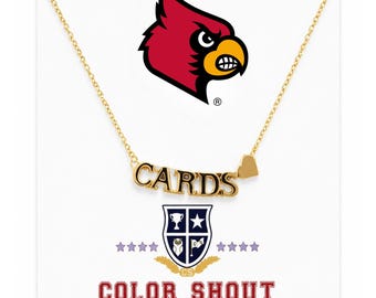May include: A gold-toned necklace featuring a pendant that spells out the word CARDS in capital letters with a small heart shape attached to the right side. Above the necklace is a red cardinal bird logo and below is a shield emblem with the text COLOR SHOUT.