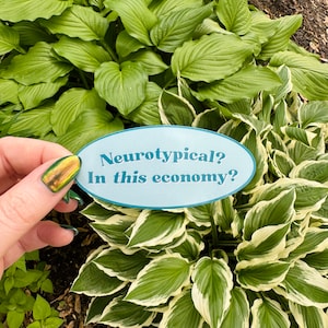 May include: A blue and white oval sticker with the text "Neurotypical? In this economy?" on a background of green and white hosta plants.