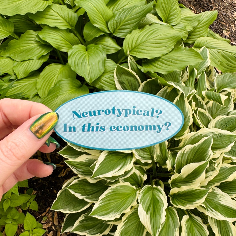 May include: A blue and white oval sticker with the text "Neurotypical? In this economy?" on a background of green and white hosta plants.