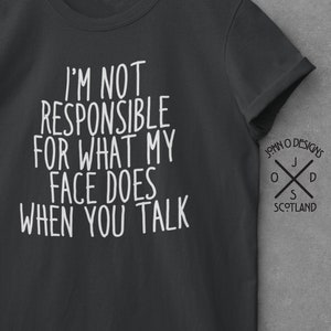 May include: A dark gray t-shirt with white text that reads "I'm not responsible for what my face does when you talk". The shirt has a crew neck and short sleeves. The back of the shirt has a small logo that reads "John O' Designs" with a cross and the words "Scotland".