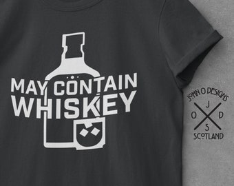 May include: A dark gray t-shirt with a white graphic of a whiskey bottle and glass with ice cubes. The text "MAY CONTAIN WHISKEY" is printed on the shirt. The John O' Designs logo is printed on the right sleeve.