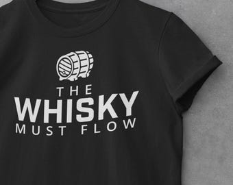 May include: Black t-shirt with the white text "THE WHISKY MUST FLOW" and a barrel graphic. The shirt is displayed on a wooden hanger against a gray background. The sleeves are cuffed.