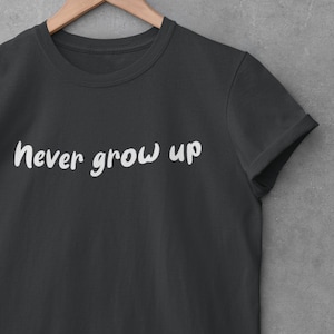 Puede incluir: Una camiseta negra con el texto "never grow up" impreso en blanco en la parte delantera.