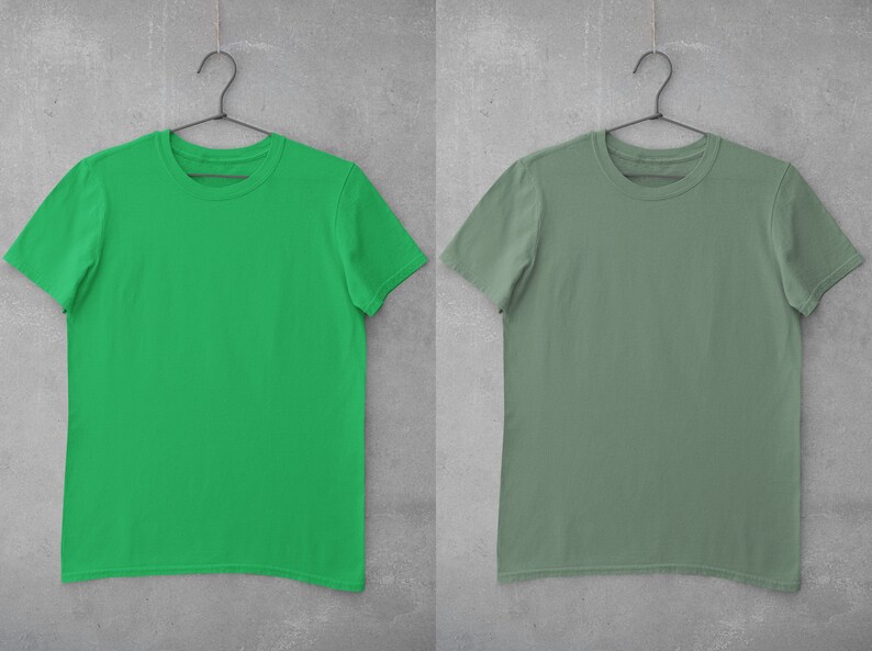 May include: Two plain t-shirts hanging on hangers against a gray concrete wall. The t-shirt on the left is bright green, and the t-shirt on the right is a muted sage green.