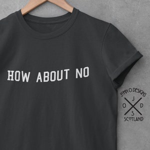 Puede incluir: Una camiseta gris oscuro con el texto "HOW ABOUT NO" impreso en blanco en la parte delantera. La camiseta tiene un pequeño logotipo en la manga derecha que dice "JOHN O DESIGNS" con una cruz y las letras "J O D S" y la palabra "SCOTLAND" debajo.