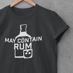 May include: A dark gray t-shirt with a white graphic of a bottle and glass with the text "MAY CONTAIN RUM".