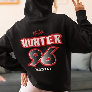 May include: Black hooded sweatshirt with a red and white graphic design. The graphic features the text "HUNTER 96" with checkered flags and the word "HONDA" underneath.