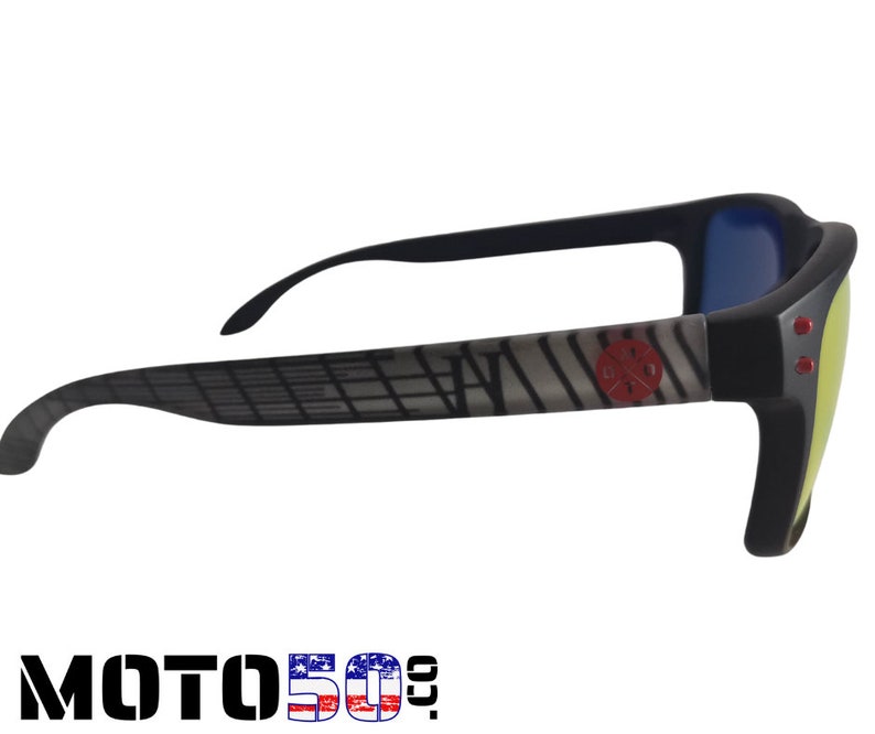 May include: Black sunglasses with a gray and white patterned frame and red accents. The lenses are yellow and blue.