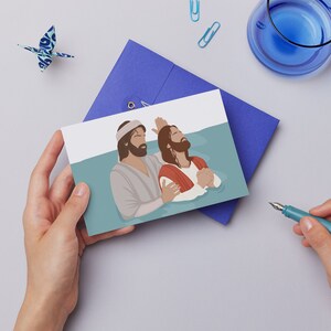 May include: A card with an illustration of two men in water. One man is wearing a white robe and is holding the other man's hand. The other man is wearing a red robe and has his arms raised. The water is blue and the background is white.