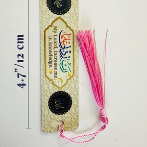 May include: A bookmark with a gold and white background featuring Islamic calligraphy and the text "My Lord, increase me in knowledge." The bookmark has a pink tassel and measures 4.7 inches by 1.26 inches.