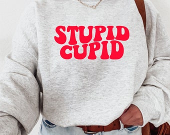 Sweter walentynkowy. Bluza Stupid Cupid. Odlotowy sweter graficzny. Pomysł na prezent. Uroczy, modny okrągły dekolt. Zabawna pojedyncza koszula. Dopasowanie uniseks.