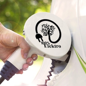May include: A white electric car charging station with a black plug and a sticker that says "100% Elektro" with a tree and plug design.