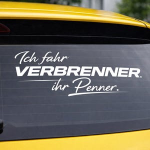 Peut inclure: Autocollant blanc sur la vitre arrière d'une voiture jaune. Le texte allemand stylisé sur l'autocollant se lit "Ich fahr VERBRENNER ihr Penner."