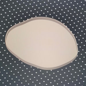 May include: A white, round, blank, paper or plastic sign with a slightly irregular shape. The sign is on a black background with white polka dots.