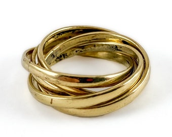 May include: A gold-toned interlocking ring with multiple bands. The ring is made of a smooth metal and has a polished finish.