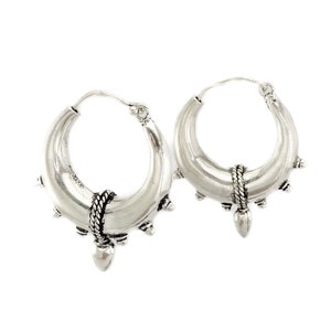 May include: Silver hoop earrings with a textured design and a pointed detail at the bottom.