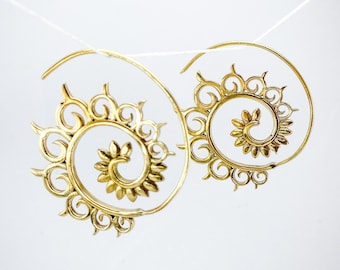 May include: A pair of gold-colored spiral earrings with a sunburst design. The earrings are suspended against a white background, showcasing their intricate details and elegant form. The earrings have a floral design in the center of the spiral.