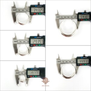 May include: Close-up of a silver hoop earring being measured with a digital caliper. The caliper reads 34.327 mm, 29.357 mm, 19.777 mm, 54.10 mm, and 44.41 mm.