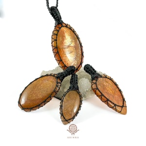 Può includere: Quattro ciondoli in pietra di sole con cordoncino in macramé nero. Le pietre sono ovali e hanno un colore marrone rossiccio con un bagliore dorato scintillante.