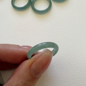 May include: A set of ten jade green rings. The rings are smooth and polished, and they are all the same size.