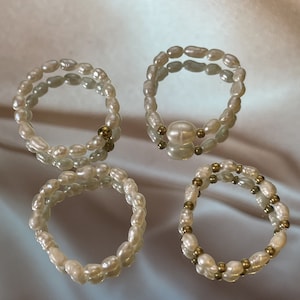 May include: Four pearl bracelets with gold accents. Two bracelets are made of white pearls and two are made of white pearls and gold beads.