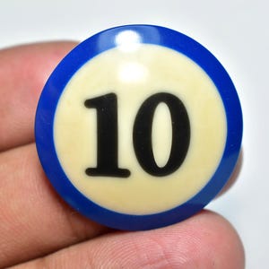 Puede incluir: Una bola de billar azul y crema con el número 10 en negro. La bola tiene un anillo exterior azul y un centro crema. El número 10 se muestra de forma destacada en una fuente negra en negrita.