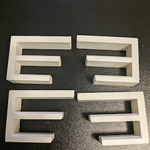 May include: Four white shelf units with three shelves each. The shelves are made of a smooth, white material and are designed to be mounted on a wall.