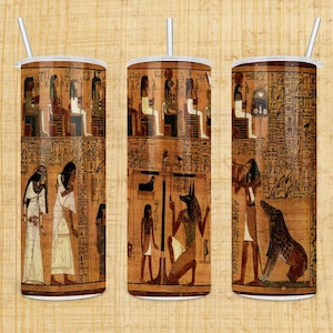 May include: Three stainless steel tumblers with a design of ancient Egyptian hieroglyphics and figures. The design features a scene of a pharaoh, a jackal-headed god, and other figures.