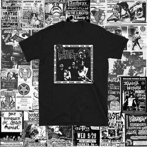 May include: Black t-shirt featuring a graphic with the text "BIG BUSINESS AND THE GOVERNMENT ARE BOTH THE FUCKING SAME, THEY BOTH SHIT UPON FREEDOM, PEACE AND EQUALITY." The shirt is surrounded by various black and white concert posters.
