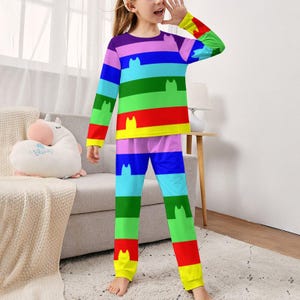 May include: A vibrant pajama set with a rainbow striped design and cat motifs. The long-sleeved top and trousers display horizontal stripes in shades of purple, blue, green, yellow, and red. White cat silhouettes are featured throughout the design.