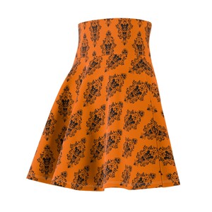 May include: An orange skirt with a black and white pattern of a haunted house and Mickey Mouse heads.