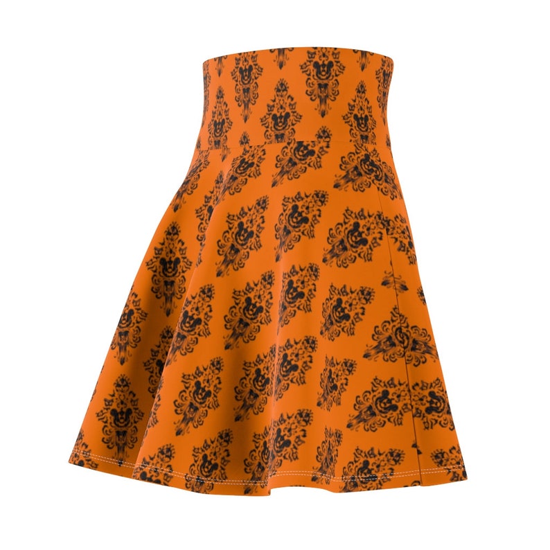 May include: An orange skirt with a black and white pattern of a haunted house and Mickey Mouse heads.
