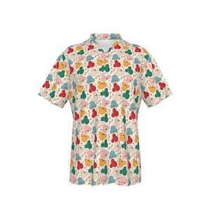 May include: A short-sleeved button-down shirt with a cream background and a repeating pattern of colorful, abstract shapes. The shapes are in shades of red, yellow, green, pink, and blue.