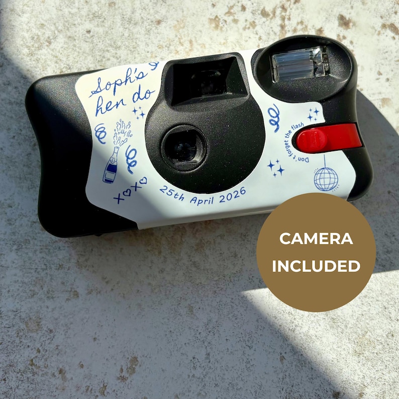 May include: A black and white disposable camera featuring a custom sticker with blue ink illustrations of a champagne bottle, disco ball, and stars. The text reads Soph's hen do, 25th April 2026, and Don't forget the flash. It has a red shutter button.