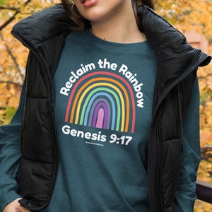 以下が含まれることがあります： レインボーのグラフィックと「Reclaim the Rainbow Genesis 9:17」のテキストが書かれたティール色の長袖シャツ。