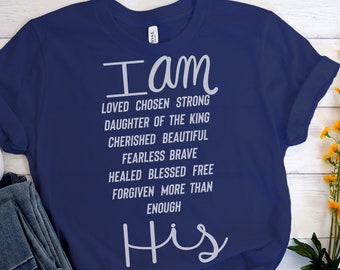 May include: Navy blue t-shirt with white text that reads "I am Loved Chosen Strong Daughter of the King Cherished Beautiful Fearless Brave Healed Blessed Free Forgiven More Than Enough His".