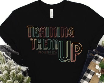 May include: Black t-shirt with a rainbow colored graphic that says "Training Them Up" with the scripture "Proverbs 22:6" underneath.