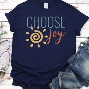 May include: A navy blue t-shirt with a yellow sun and the text "CHOOSE joy" in teal and red.