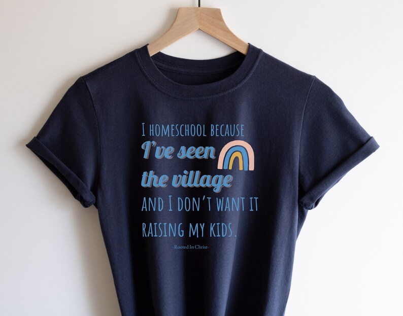 May include: A navy blue t-shirt with the text "I homeschool because I've seen the village and I don't want it raising my kids." and a rainbow graphic. The text "Rooted in Christ" is also included.