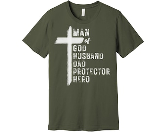 Op de afbeelding: Een groen T-shirt met een wit kruis en de tekst "Man of God Husband Dad Protector Hero".